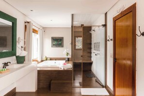 A modern bathroom with a large bathtub, a shower area, and a glass-enclosed walk-in shower. - Casa da Lua Pousada (Alto Paraíso de Goiás)