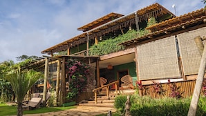 Una casa a due piani con una scala in legno, un'area salotto esterna e un giardino.