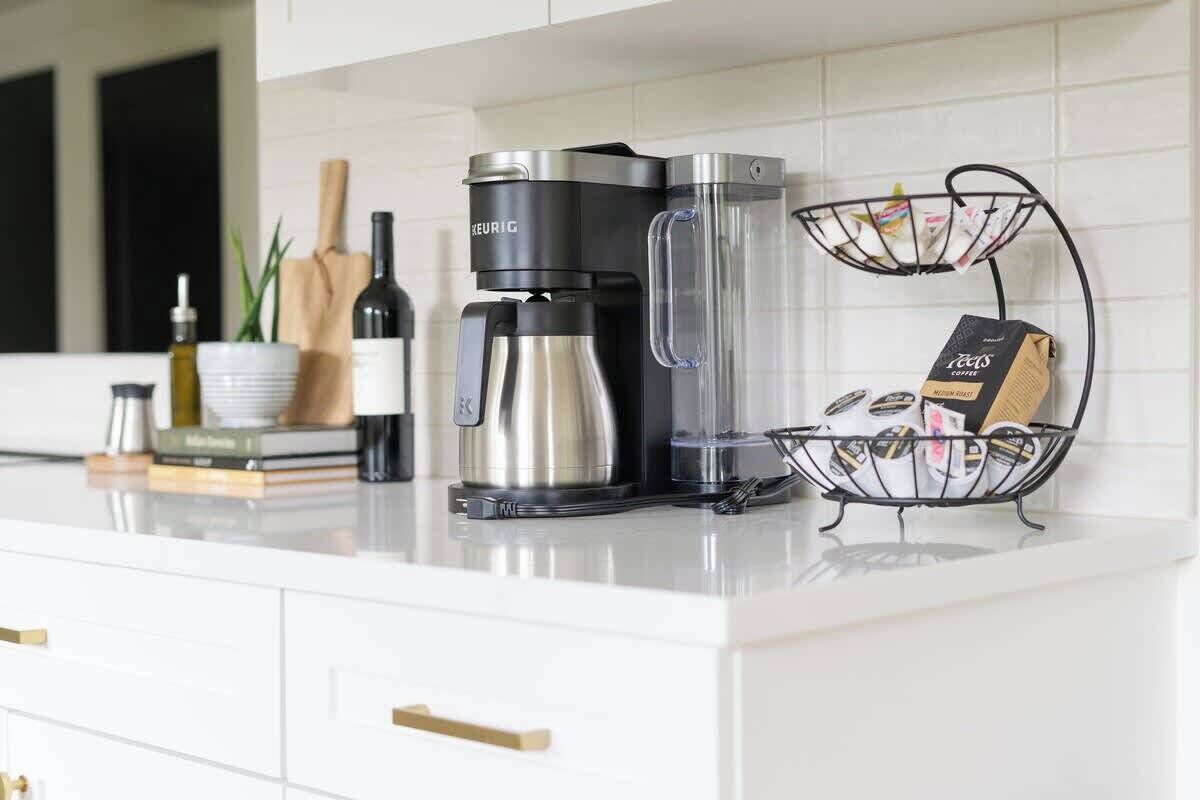 Un comptoir de cuisine avec une machine à café Keurig, une verseuse en verre et un porte-filtre.