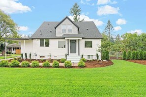 A two-story house with a front porch, a small garden, and a well-maintained lawn. - Contemporary Camas Retreat (Camas)