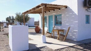 A white building with blue accents, a wooden pergola, and a table with chairs outside. - Finca Rosablanca (Tunuyan)