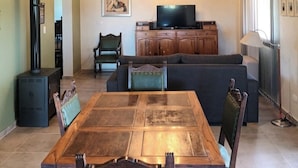 A dining area with a wooden table and chairs, a television, and a chandelier. - Finca Rosablanca (Tunuyan)