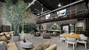 A spacious living area with a large tree, modern furniture, and a kitchen in the background.