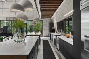 A modern kitchen with a central island, stainless steel appliances, and pendant lighting. - 2.5-Acre Modern Industrial Estate Tennis, Gym, Pool, Pickle Ball, Hot Tub, Bocce (Naples)