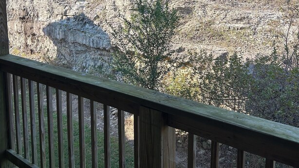 Eine Holzdielen-Terrasse mit Blick auf eine felsige Landschaft und vereinzelte Vegetation.