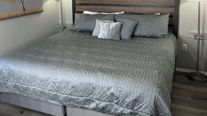 Ein Schlafzimmer mit einem Bett, einem Deckenventilator, einer Wandleuchte und einem dekorativen Wandbild.