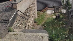 Vista de la montaña con un coche aparcado en una carretera, una bandera y un edificio con techo inclinado.