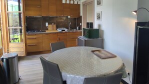 Una cocina compacta con armarios de madera, una mesa de comedor con sillas y un refrigerador pequeño.