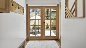 A hallway with a wooden door leading to a patio area.