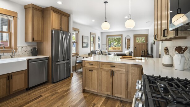 A modern kitchen with wooden cabinets, stainless steel appliances, and pendant lighting.
