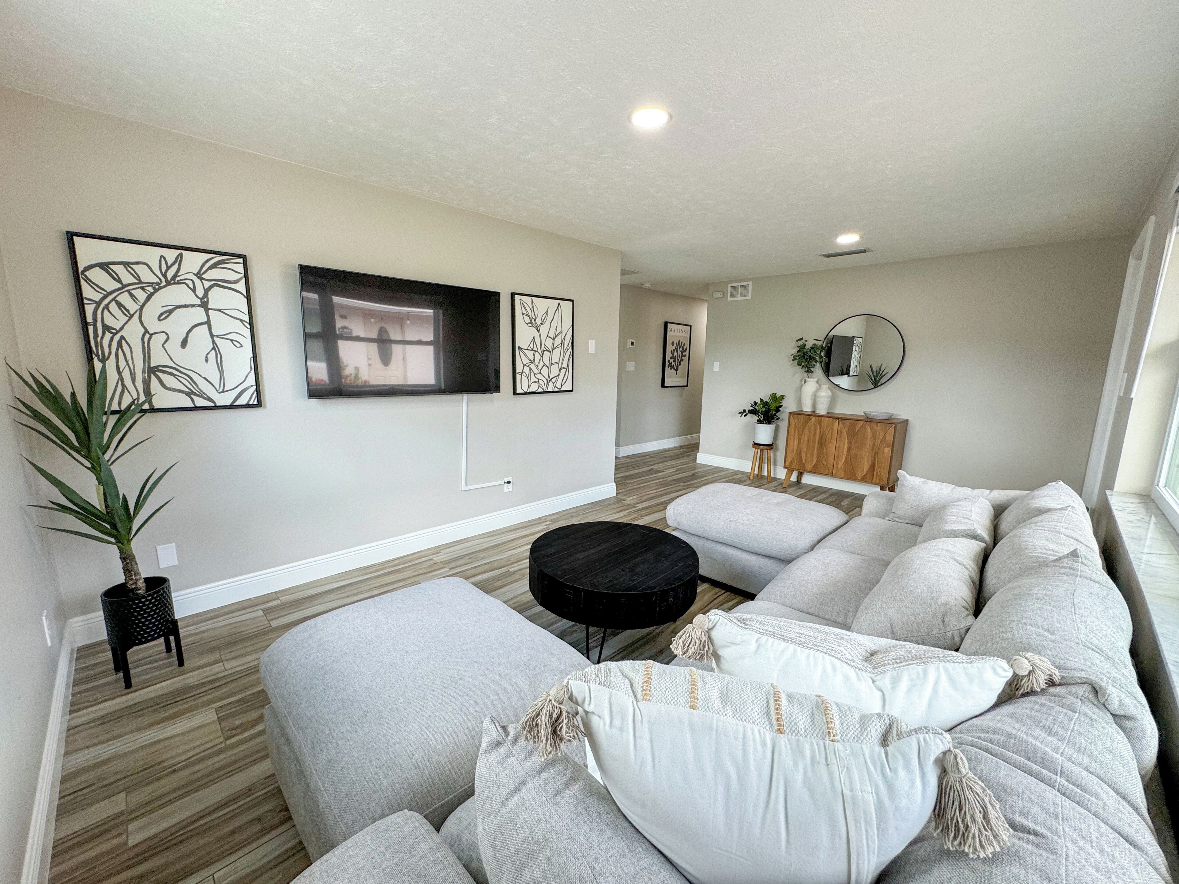 A modern living room with a sectional sofa, a black coffee table, and artwork on the walls.