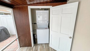 A laundry room with a washer and dryer, wooden walls, and a tiled floor.