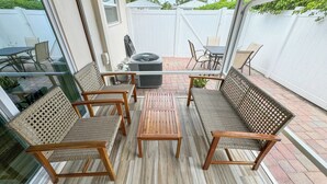 A covered patio area with wicker furniture, a central table, and a grill.