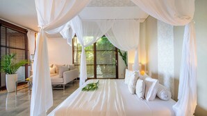 Ein Schlafzimmer mit einem Baldachinbett, einer Couch und einem Blumentopf.