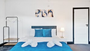 A hotel room with a bed, a bedside table with a lamp, a wall-mounted artwork, and a door. - MODERN DUPLEX APARTMENT LOCATED NEAR CITY CENTRE - FREE PARKING, WI FI & NETFLIX (Reading)