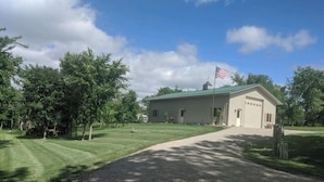 A building with a green roof and an American flag, surrounded by trees and a well-maintained lawn. - Copper Lodge - Lake Miltona
License #:  1999 (Miltona)
