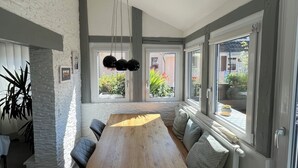 Un comedor moderno con una larga mesa de madera, bancos acolchados y una lámpara colgante.