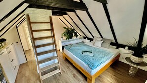 Un dormitorio con cama tipo litera, escalera de madera y un pequeño espacio de escritorio.