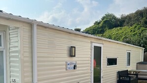 A mobile home with a sliding door, a small window, and a sign that reads "Relax, you're at the beach."