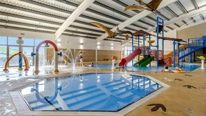 An indoor swimming pool with slides and water features.