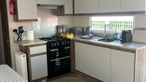 A compact kitchen with white cabinets, a black stove, and a window providing natural light.