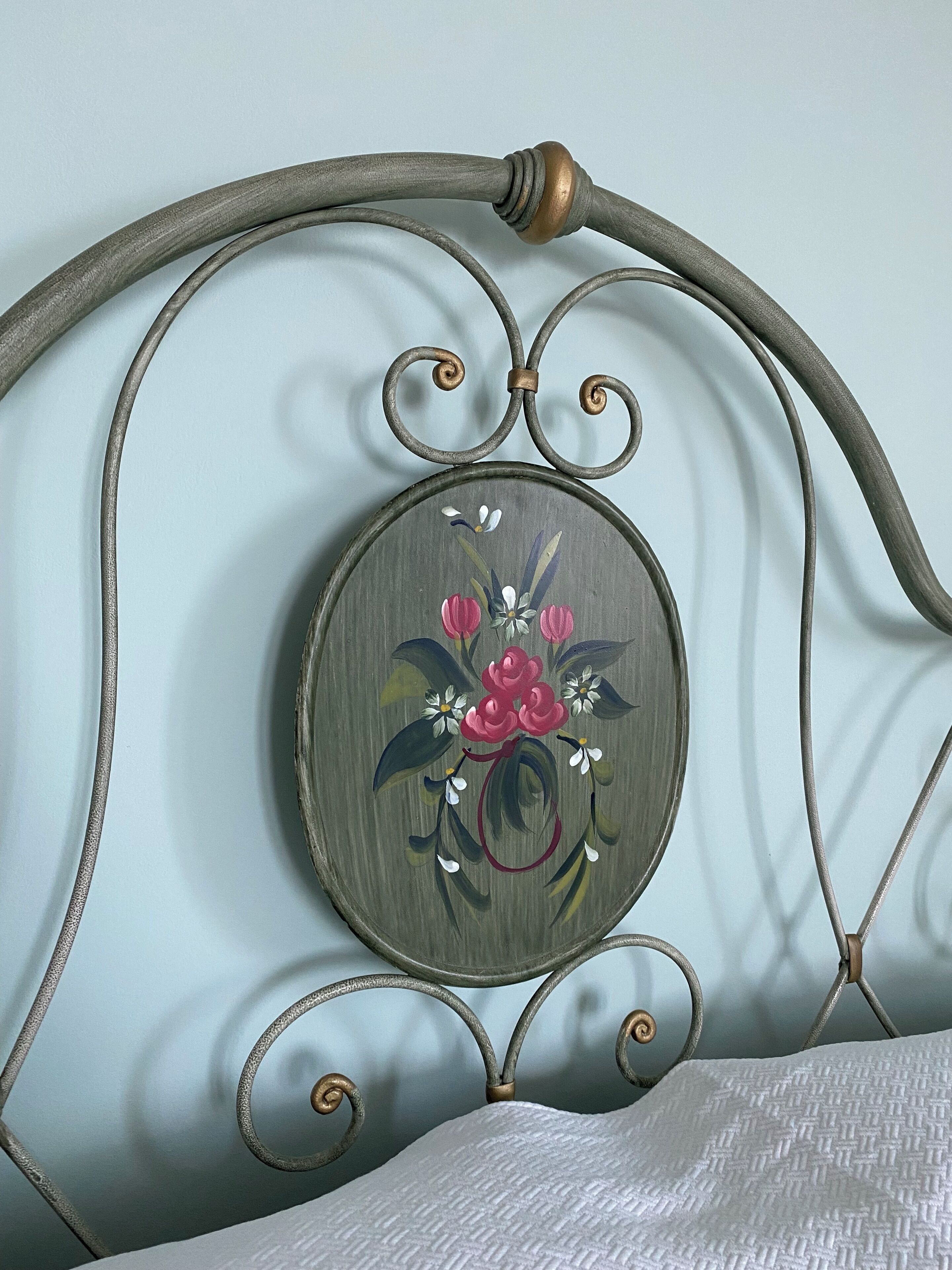 Struttura letto in metallo con un'opera d'arte floreale decorativa sulla testata.