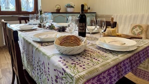 Une table à manger dressée avec des assiettes, des verres, une bouteille de vin et un panier de pain.