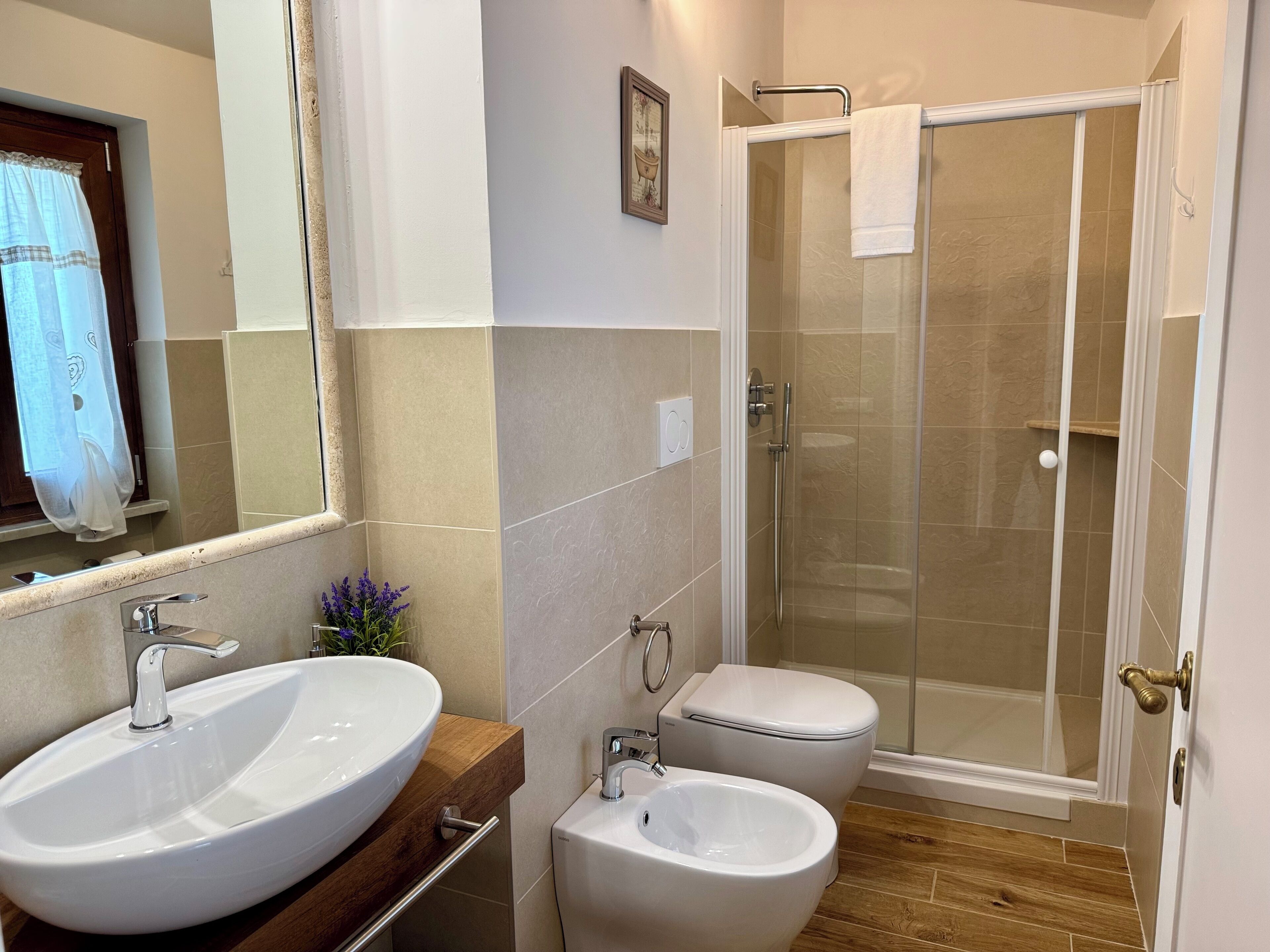 Une salle de bain moderne dotée d’un grand lavabo, d’un bidet et d’une douche à parois de verre.