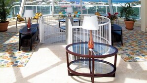 Un balcón amplio con techo de cristal que ofrece una vista despejada del mar y edificios.