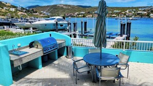 An outdoor patio with a grill, seating, and a view of the marina and water. - ☀️🌴Spinnaker 1312 by IRE Vacations - 2 bedroom Condo with Resort Amenities👙 (Oyster Pond)