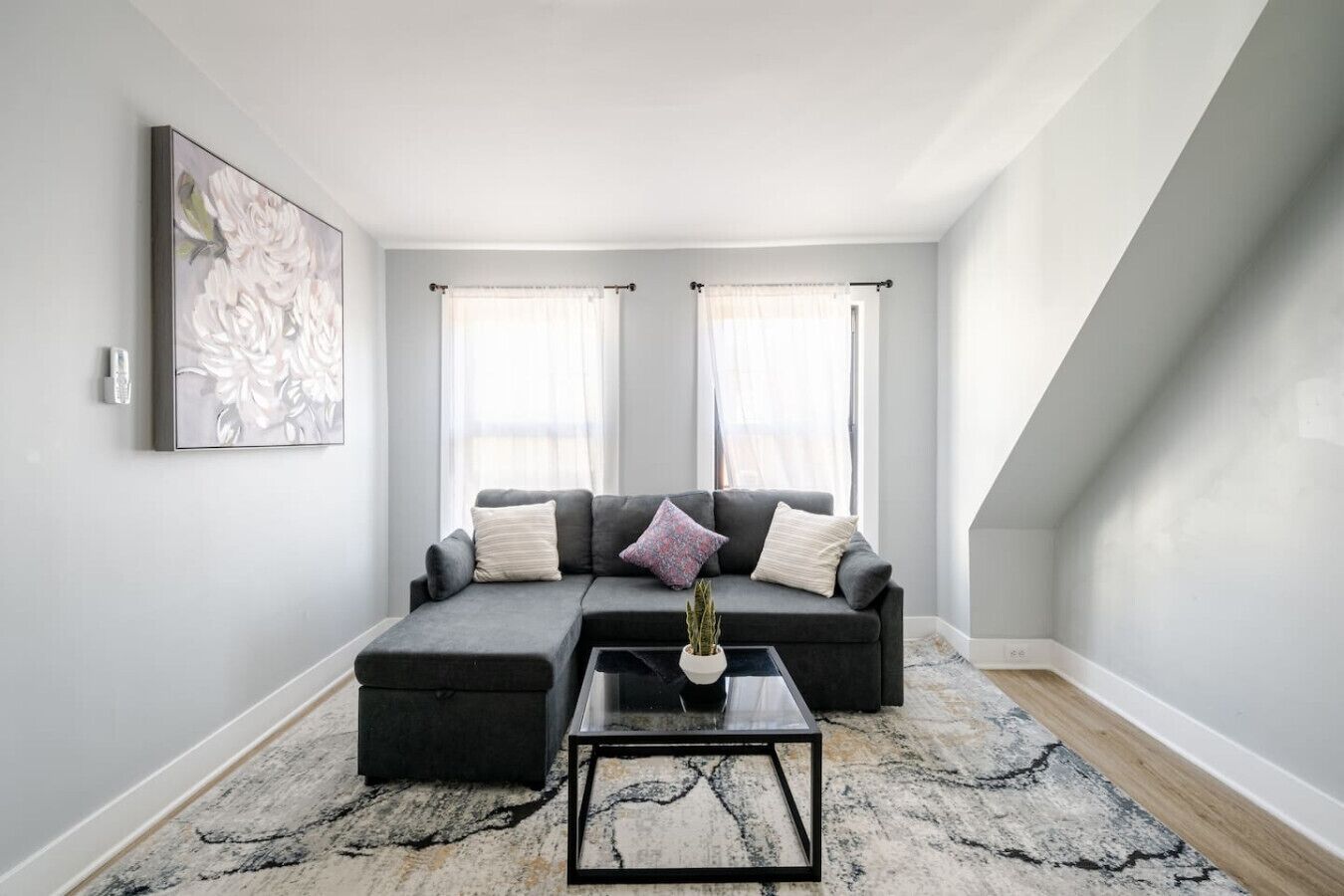 A modern living room with a sectional sofa, a coffee table, and a large abstract painting on the wall.