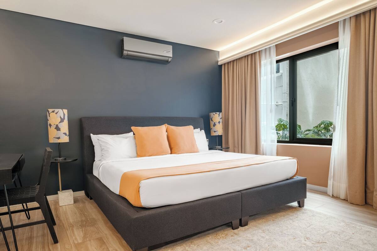 Een moderne hotelkamer met een groot bed, een bureau en een raam met gordijnen.