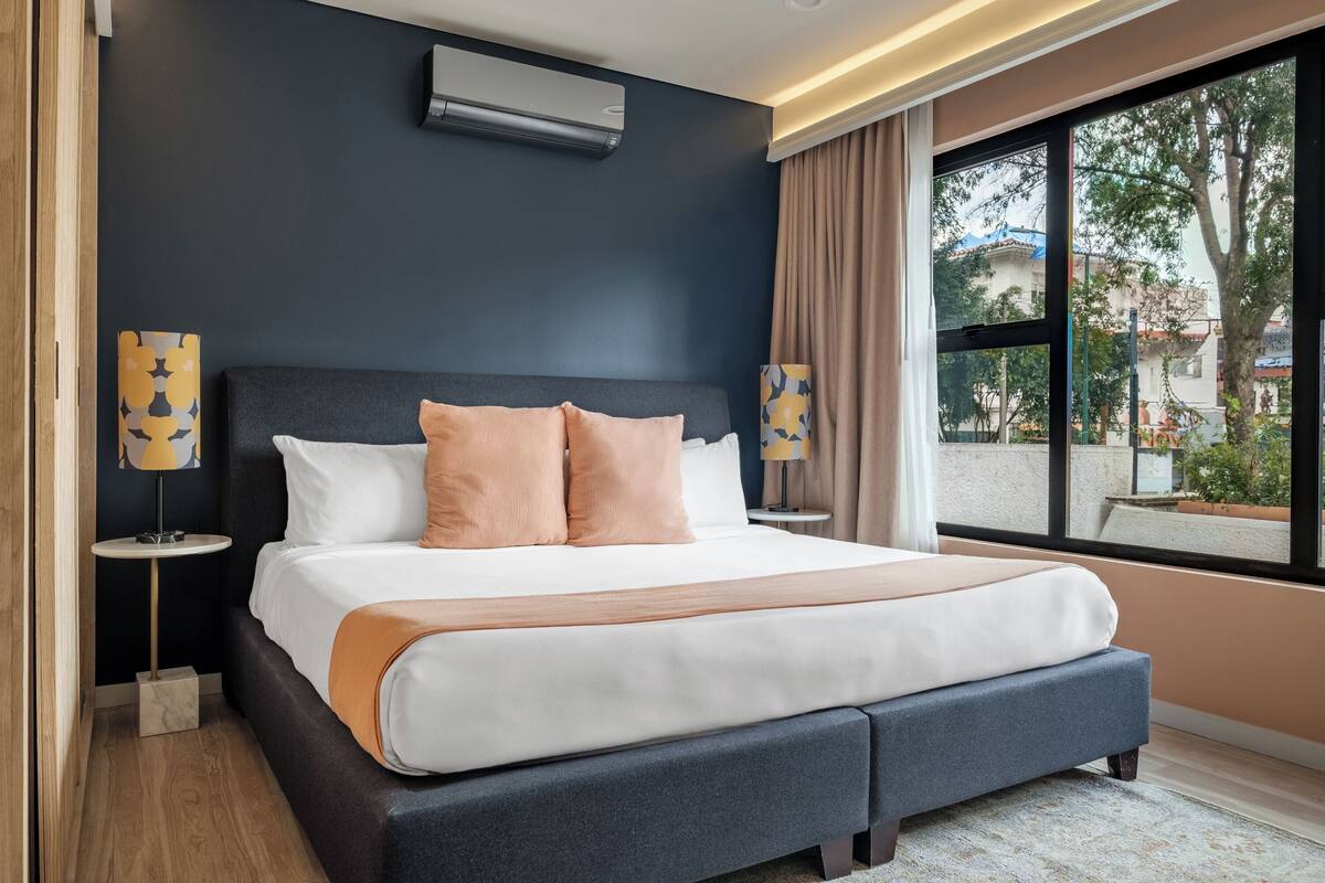 Een moderne hotelkamer met een groot bed, een raam met uitzicht en een airconditioning aan de muur.