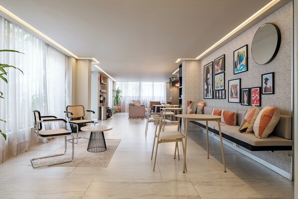Una sala de estar moderna con un sofá, sillas, una mesa de centro y un comedor. Hay estanterías y obras de arte en las paredes.