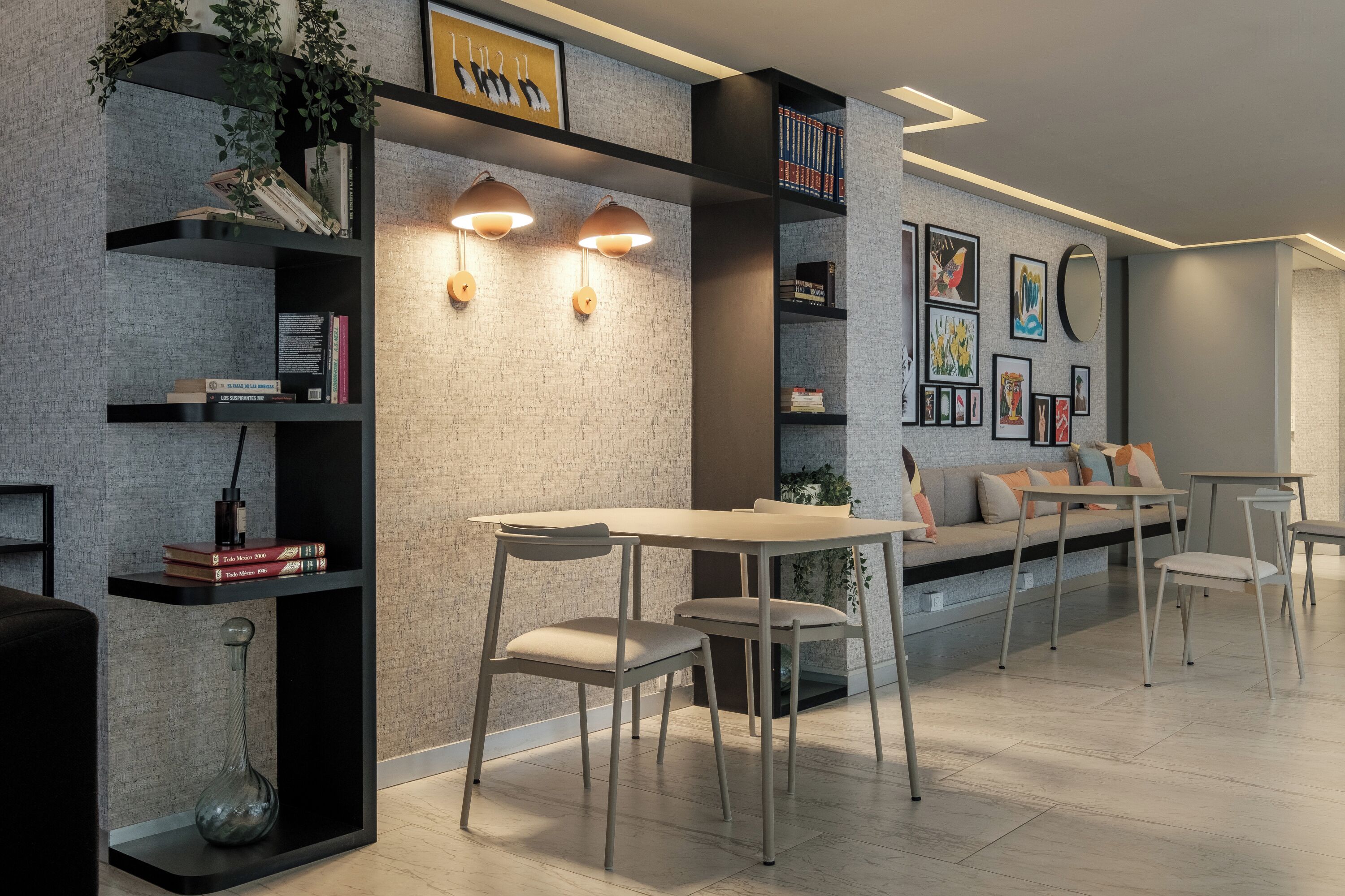 Un salon moderne avec un coin repas, comprenant un canapé, des fauteuils, une table basse et des étagères décoratives.
