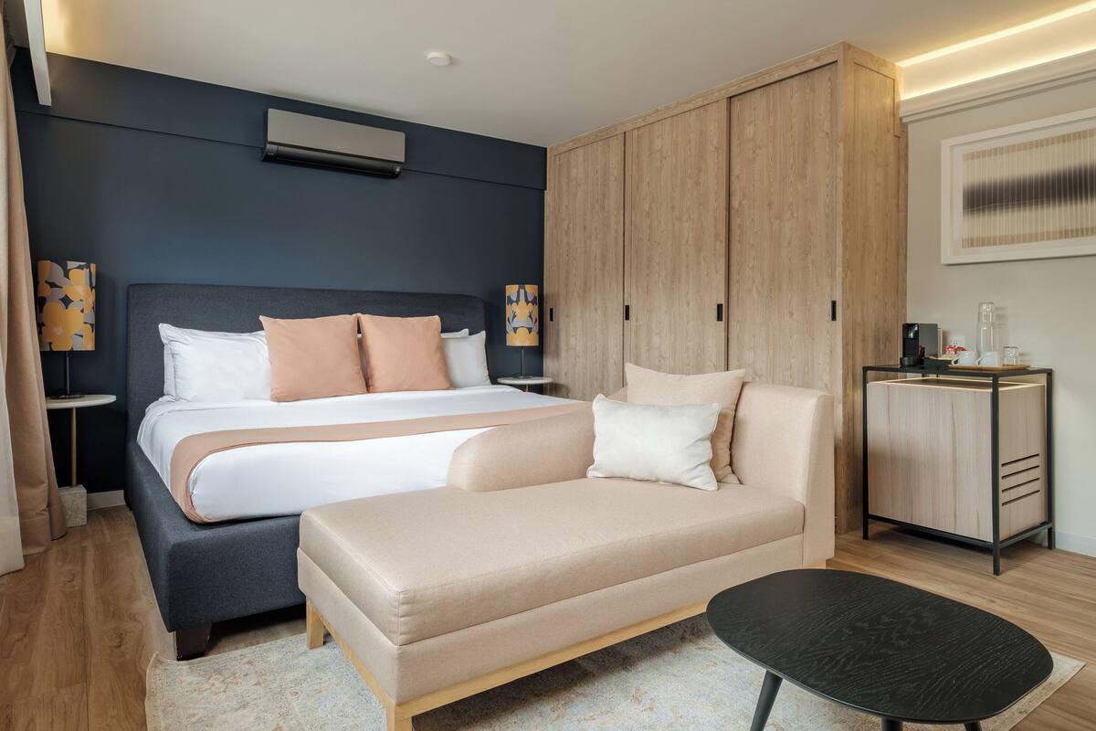 Een moderne slaapkamer met een bed, een bank, een nachtkastje en een garderobe.