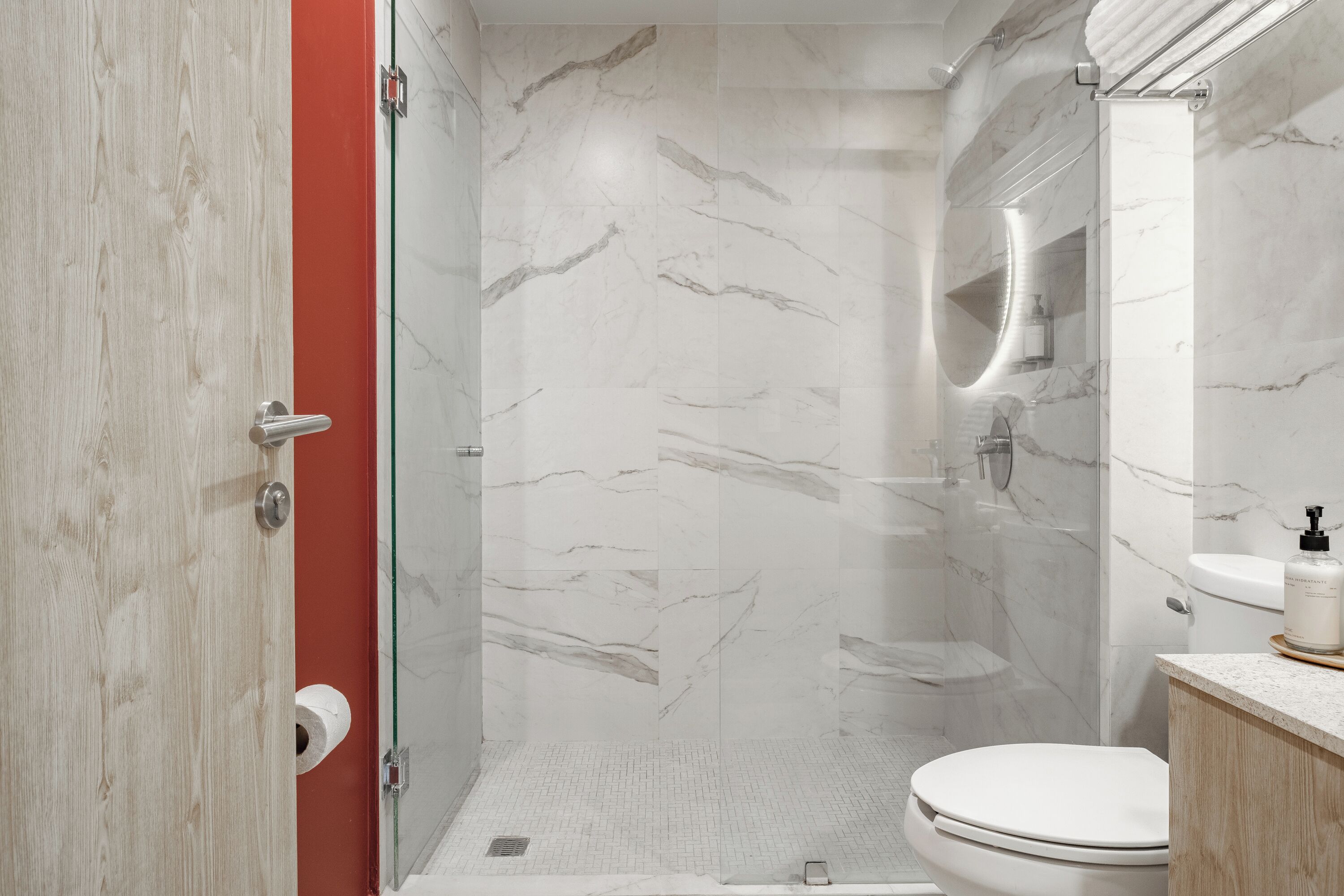 A modern bathroom with a shower, toilet, and sink.
