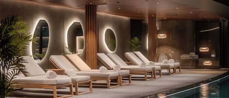 A modern indoor pool area with lounge chairs and a long pool.