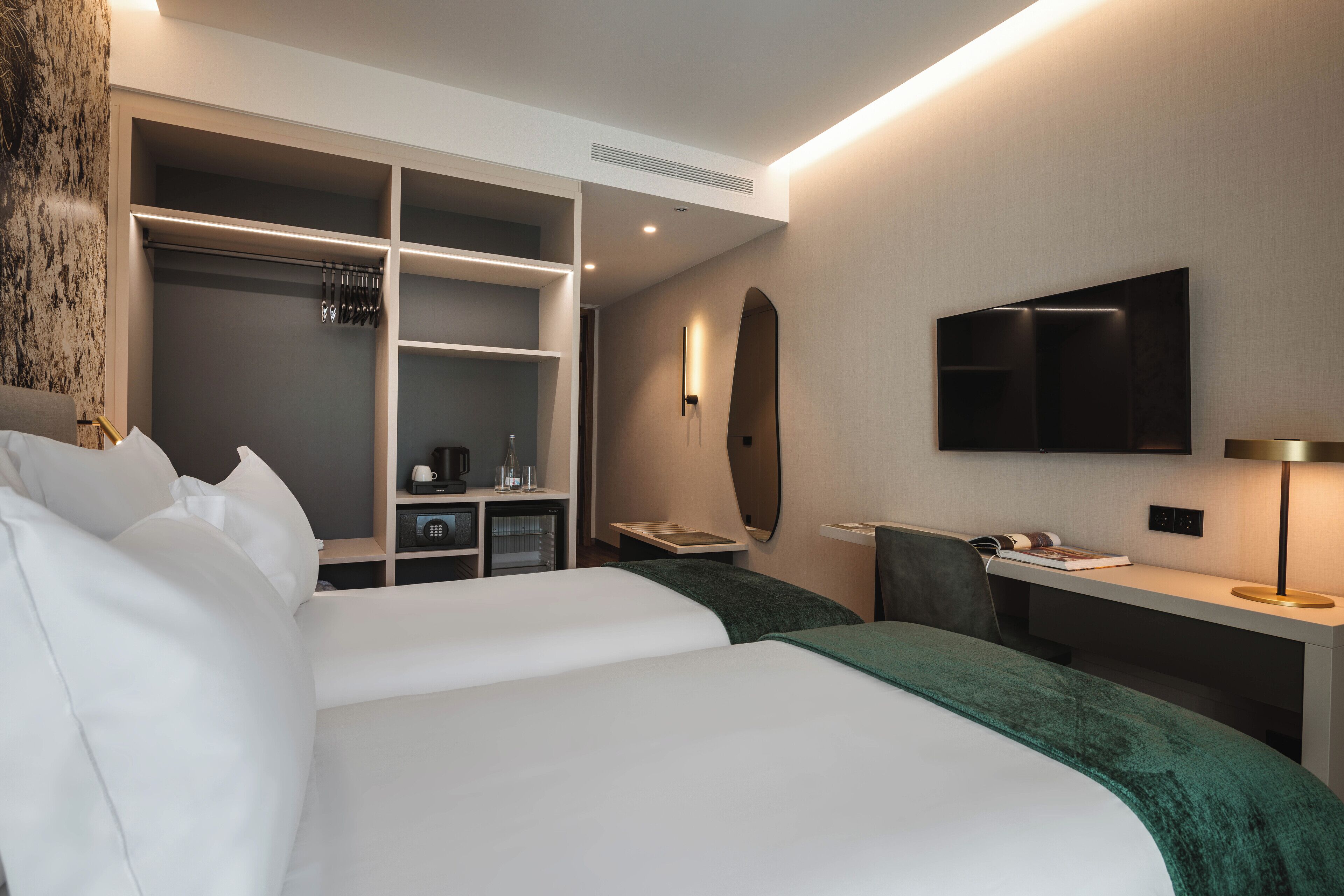 A hotel room with a large bed, a desk, a TV, and a walk-in closet.