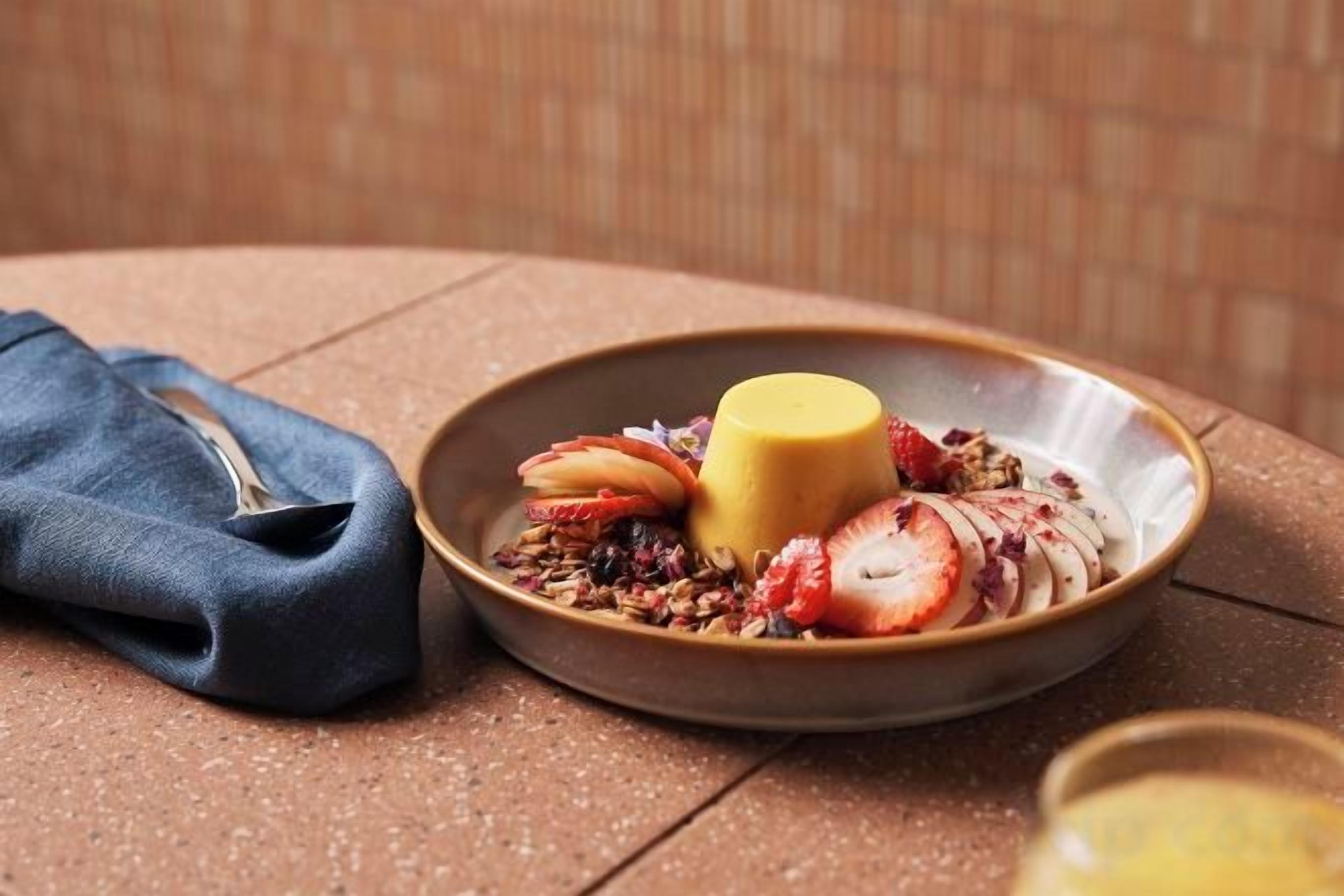 A plate with a dessert and fruit on a table.