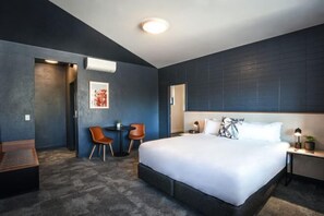 A modern hotel room with a large bed, a desk with a chair, and a small table with two chairs. - HotelMOTEL Adelaide (Adelaide)