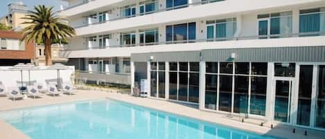 Un hotel moderno con piscina, varios pisos y una palmera.