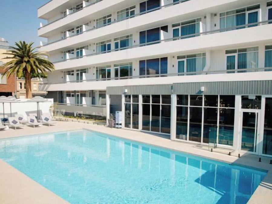 Un hotel moderno con piscina, varios pisos y una palmera.