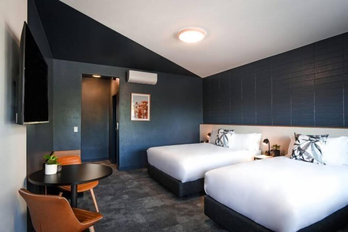 Hotellihuone, jossa on kaksi sänkyä, työpöytä ja tuoli.