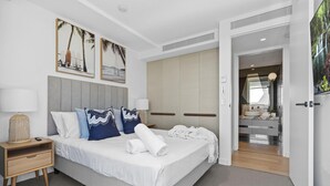 A modern hotel room with a large bed, a bedside table with a lamp, and a view into the bathroom.