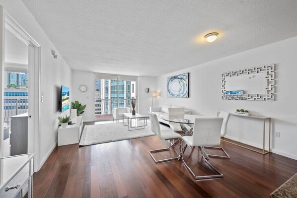 Een moderne woonkamer met een eethoek, grote ramen en uitzicht op de stad.