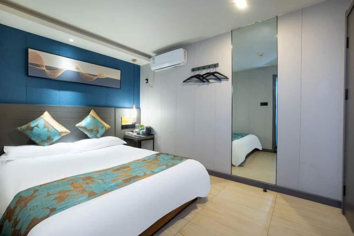 Una habitación de hotel con cama, mesita de noche, aire acondicionado instalado en la pared y un espejo grande.