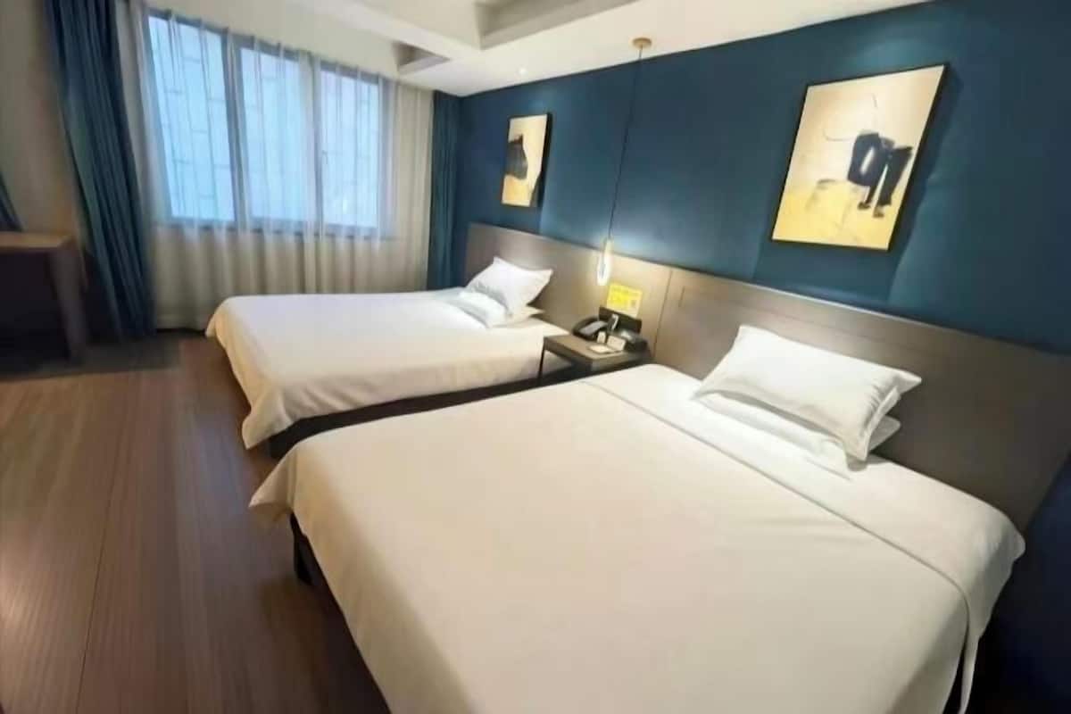 Una habitación de hotel con dos camas, una mesita de noche con un teléfono y obras de arte en las paredes.