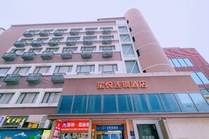 Un hotel con varios balcones, un letrero llamativo y un escaparate con diversas tiendas.