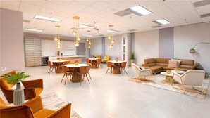 A spacious, modern interior with a central dining area, multiple seating arrangements, and contemporary lighting fixtures.